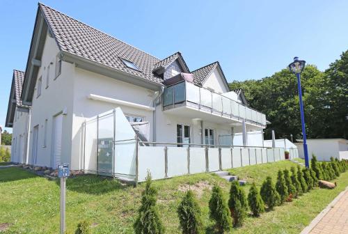 ein weißes Haus mit einem Zaun davor in der Unterkunft Haus Sonne - FeWo 01 Sandperle in Thiessow