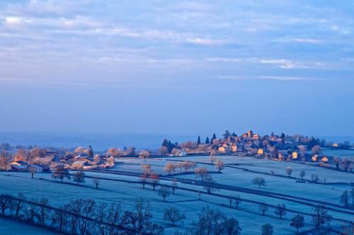 un champ enneigé avec des maisons au loin dans l'établissement Les Folies d'Hélène, à Mailly