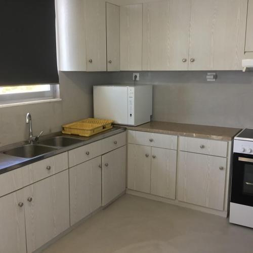 a kitchen with white cabinets and a sink at Saronicos Gulf View in Anavissos in Anavissos