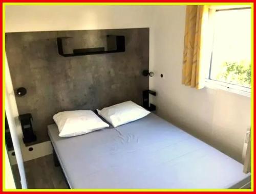 - un lit avec deux oreillers dans une chambre dotée d'une fenêtre dans l'établissement Paradis familial avec piscine à Saint-Denis-d'Oléron, à Saint-Denis-dʼOléron