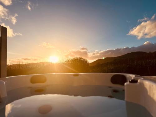 a bath tub with the sun setting in the background at Kinnaird Woodland Lodges in Pitlochry