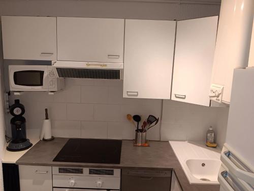 une petite cuisine avec des armoires blanches et un évier dans l'établissement Appartement lumineux à Agde avec vue sur la mer - 34 m², au Cap d'Agde