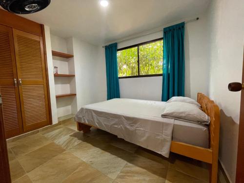 a bedroom with a bed with blue curtains and a window at Casa Boutique Rincon in San Onofre
