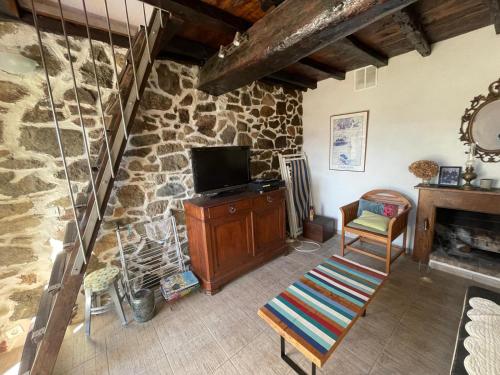 un salon avec une télévision et un mur en pierre dans l'établissement Letia Noce, à Chidazzo