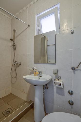 a bathroom with a sink and a mirror and a shower at Apartmani Marina in Sutomore