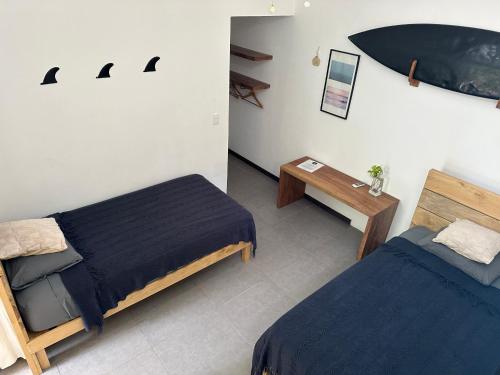 een kamer met twee bedden en een tafel erin bij El Chante Surf House in Santa Teresa Beach