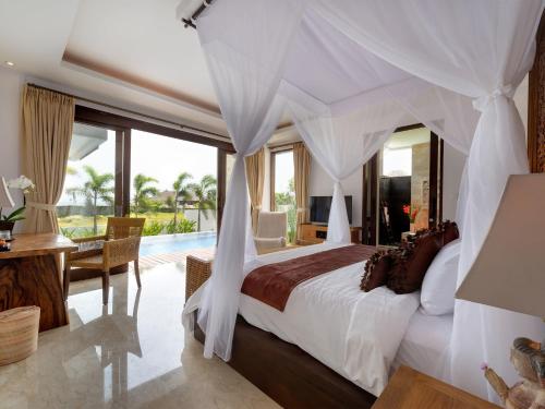 a bedroom with a large bed and a pool at Villa Luwih in Canggu
