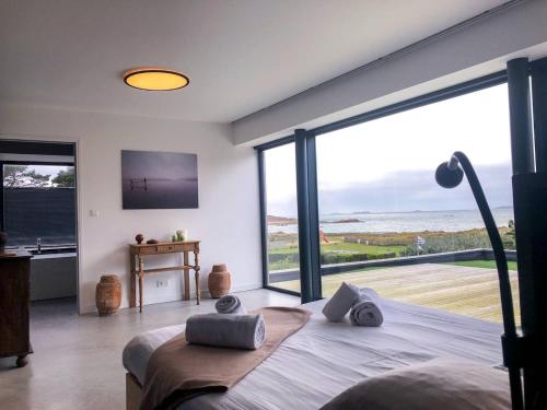 une chambre avec un lit et une grande fenêtre en verre dans l'établissement Grande dune, Grande Dune Sea view rental in Port, à Penvénan