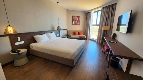 a hotel room with a bed and a desk at Apec Mandala Mui Ne Phan Thiet in Ấp Long Sơn