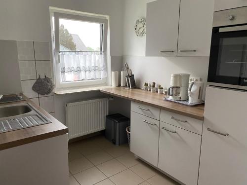 een keuken met witte kasten, een wastafel en een raam bij Ferienwohnung Malk in Traben-Trarbach
