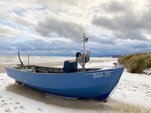 un bateau bleu assis sur le sable sur une plage dans l'établissement Haus Meeresblick A 2 05 Baabedos mit Balkon, à Baabe