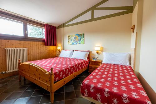 2 camas en una habitación pequeña con sábanas rojas en RESIDENCE SERRADA en Serrada