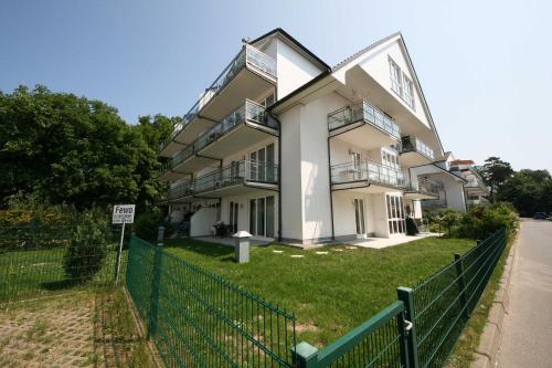 un gran edificio blanco con una valla delante en Ferienwohnung 17 am Mönchgraben mit Balkon, en Baabe