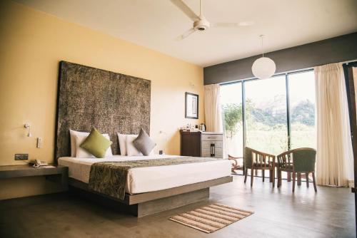 1 dormitorio con 1 cama, mesa y sillas en Sigiriya King's Resort en Sigiriya
