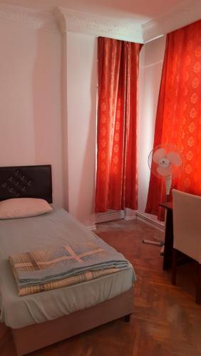 1 dormitorio con cortinas rojas, 1 cama y 1 mesa en Şirinevler Guest house, en Estambul