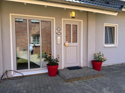 una casa con dos macetas delante de una puerta en Gästehaus am Brook mit 5 Ferienwohnungen, en Moritzdorf