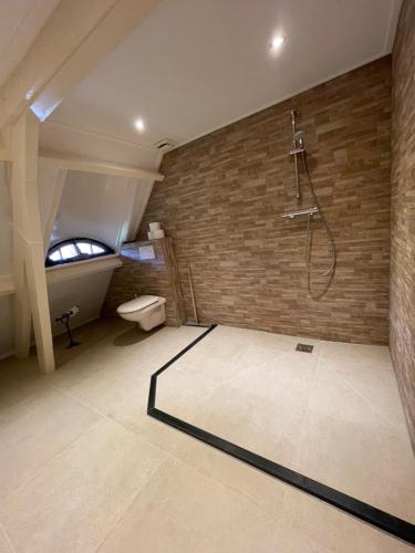 uma casa de banho com um chuveiro e uma parede de tijolos em Rio Grande Luxury Western Rooms em Terschuur