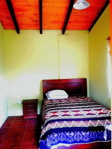 a bedroom with a bed and a wooden ceiling at Cosme Andres Pujilí in Pujilí