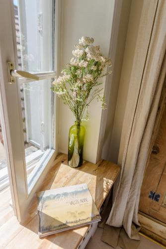 un vase de fleurs assis sur une table à côté d'une fenêtre dans l'établissement Aux Couleurs de Neuvy, à Neuvy-Saint-Sépulchre