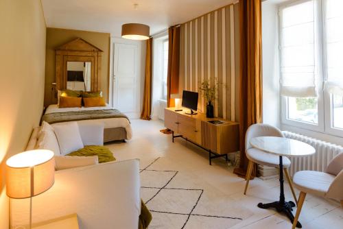 une chambre avec un lit et un bureau avec une télévision dans l'établissement Aux Couleurs de Neuvy, à Neuvy-Saint-Sépulchre