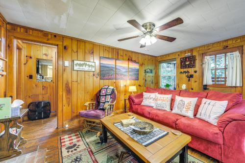 a living room with a red couch and a table at Pet-Friendly Creekside Cabin with Pool Access! in Maggie Valley