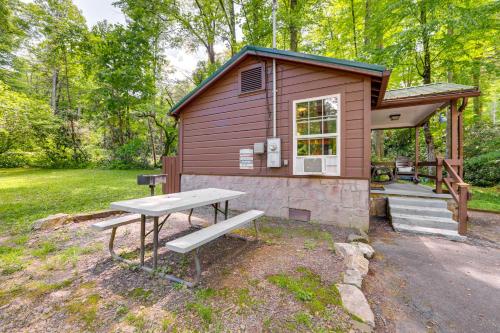 a tiny house with a picnic table and a bench at Pet-Friendly Creekside Cabin with Pool Access! in Maggie Valley