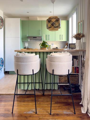une cuisine avec des placards verts et deux tabourets de bar dans l'établissement Appartement La Défense, à La Garenne-Colombes