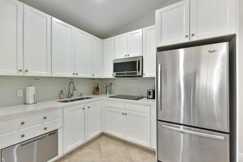 La cuisine est équipée de placards blancs et d'un réfrigérateur en acier inoxydable. dans l'établissement Cozy home with private entrance!, à Wellington