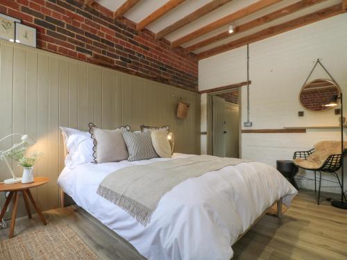 a bedroom with a large bed and a brick wall at Hazel Cottage - Fold Yards in Belper