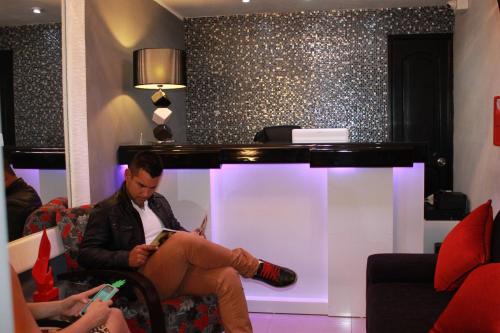 a man sitting on a couch reading a book at Hotel Venecia in Huánuco