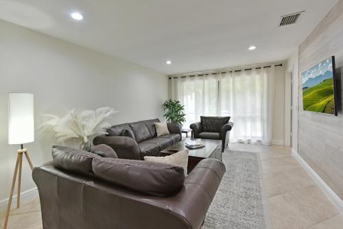 ein Wohnzimmer mit einem Ledersofa und einem TV in der Unterkunft Cozy home with private entrance! in Wellington