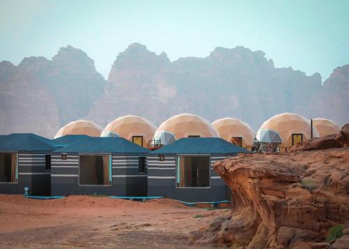 a building in the desert with mountains in the background at Faisal Wadi Rum camp in Wadi Rum
