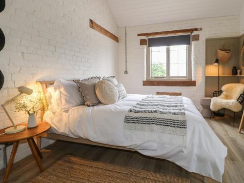 Un dormitorio con una gran cama blanca y una ventana. en Alder Cottage - Fold Yards, en Belper