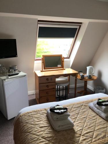 a bedroom with a bed and a desk with a laptop at Fairways Guest House in Cambridge