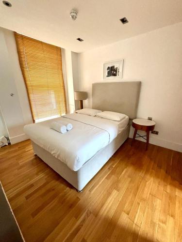 a bedroom with a large white bed and a wooden floor at 1 BR in Piccadilly Circus St James Cov1 in London
