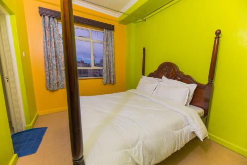 a bedroom with a bed with yellow walls and a window at Hotel Southern Blue in Nairobi