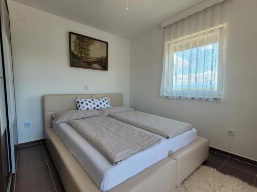 a bed in a white room with a window at Apartmani Dani in Sveti Anton