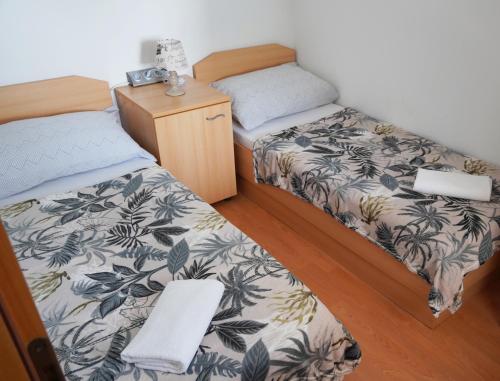 a room with two beds and a night stand at Apartman Mare in Dramalj