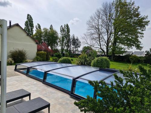 une piscine avec un toit en verre dans l'établissement Le Domaine du Moulin 28 proche Chartres, à Bailleau-lʼÉvêque