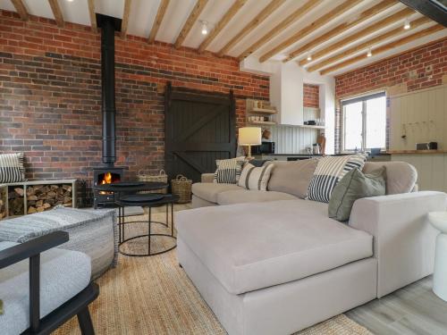 a living room with white furniture and a brick wall at Rowan Cottage - Fold Yards in Belper