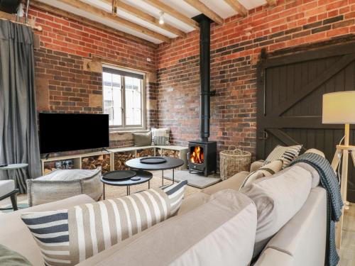 a brick walled living room with a couch and a fireplace at Rowan Cottage - Fold Yards in Belper
