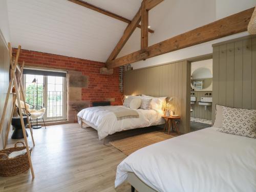 ein Schlafzimmer mit zwei Betten und einer Ziegelwand in der Unterkunft Rowan Cottage - Fold Yards in Belper
