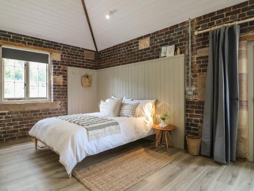 ein Schlafzimmer mit einem Bett und einer Ziegelwand in der Unterkunft Oak Cottage - Fold Yards in Belper