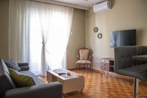 Una sala de estar con un sofá y un televisor. en Center Proluxe Apartment, en Alexandroupoli
