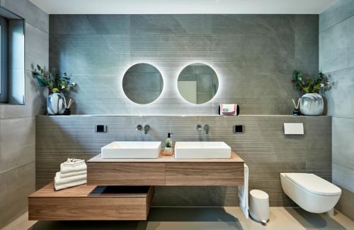a bathroom with a sink and a toilet and two mirrors at Racers Lodge Grand Prix - mit Hebebühne und Doppelgarage in Bermel