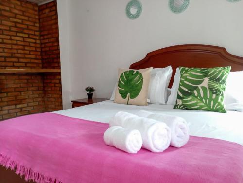 1 dormitorio con 1 cama con toallas blancas en una manta rosa en San José HOUSE, en Leticia