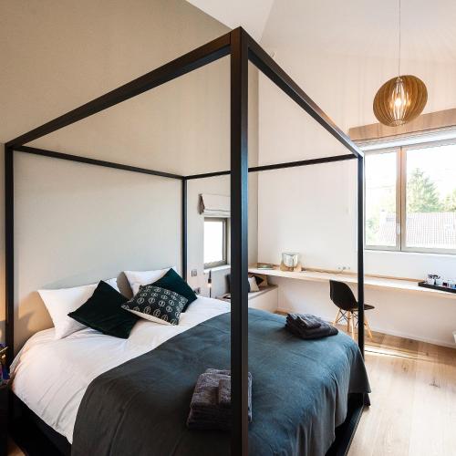 a bedroom with a canopy bed with a desk at dimensions M in Mont-Saint-Guibert