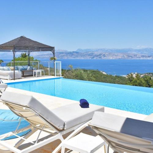 una piscina con sedie e vista sull'oceano di Villa Helion Heated Pool a Kelliá