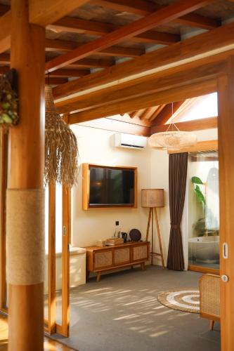 a living room with a flat screen tv and wooden ceilings at LAVILLAS JOGJA in Cebongan