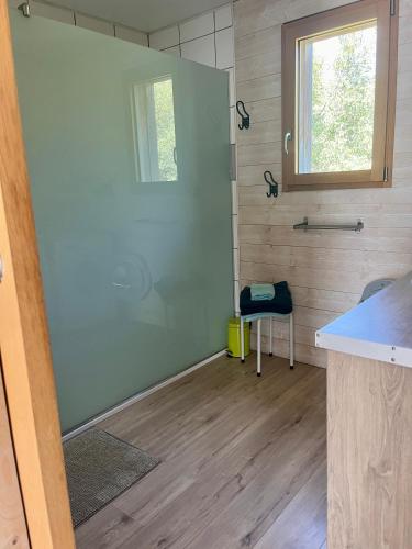 La salle de bains est pourvue d'une porte coulissante en verre avec un tabouret. dans l'établissement La Poussada, maisons écologiques avec vue mer, à Lapalme